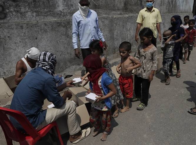 Children queue for food in a slum in Mumbai, India